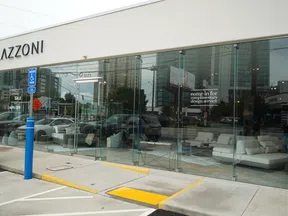 Exterior view of LAZZONI furniture store with glass facade, showcasing modern sofas and a 40% off sale sign.