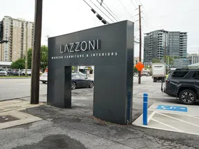 Lazzoni modern furniture and interiors black entrance sign on city street with nearby cars and buildings