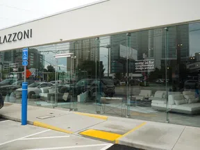 Modern Lazzoni furniture store with glass facade showcasing white sofas and complimentary design service offer.