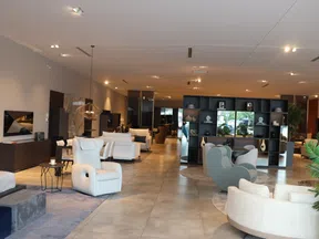 Modern furniture showroom with white recliners, cozy chairs, decorative shelving, and warm lighting.