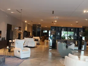 Modern furniture showroom with armchairs, sofas, decorative shelves, and ambient lighting in a spacious showroom.