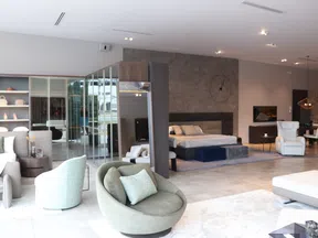 Modern open-concept living space with stylish seating, bed area, and minimalist decor in neutral tones.