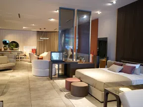 Modern spacious bedroom and living area with neutral tones, comfortable furniture, and elegant decor lighting.