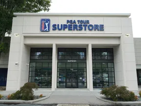 Front entrance of PGA Tour Superstore with glass doors and signage on a cloudy day