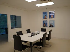 Modern conference room with white table, black chairs, water bottles, and framed honoree posters on the wall.