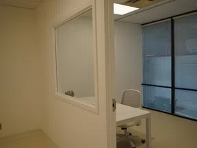 Minimalist office space with a white desk, office chair, and large window with blinds.