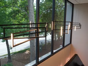 Modern geometric pendant lights hanging in front of large windows overlooking a tree-lined street.
