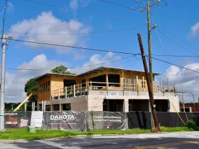 Modern commercial building under construction with Dakota contracting signage and clear blue sky.