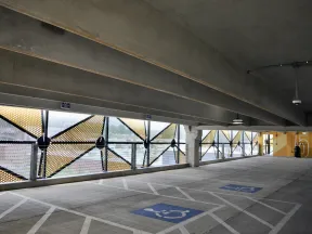 Empty multi-level parking garage with designated handicapped spaces and decorative perforated metal panels.