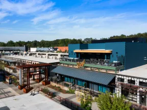 Modern commercial complex with industrial design, outdoor seating, and blue sky on a sunny day.