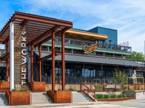 Modern building entrance at City Walk with rust-colored metal structure and Dan's restaurant sign under blue sky.