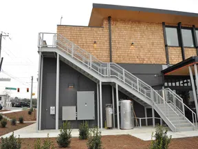 Modern commercial building with exterior metal staircase leading to second floor under natural daylight