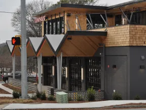 Modern Grindhouse restaurant exterior with wooden accents and geometric roof design on cloudy day