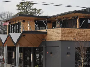 Modern two-story building with wood siding and large windows housing Grindhouse restaurant.