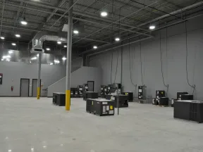 Spacious industrial warehouse with HVAC units installed on concrete floor and high ceiling lighting.