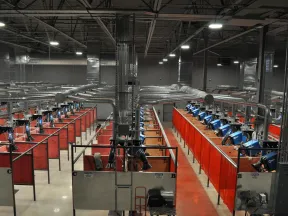 Industrial welding booths with ventilation systems in a large factory setting under bright ceiling lights