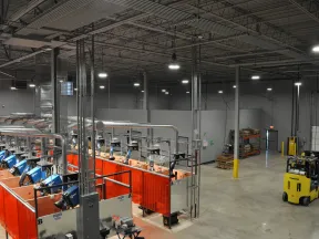 Modern industrial welding facility with multiple stations enclosed by red safety curtains and a yellow Komatsu forklift.