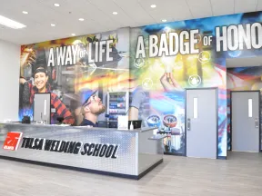Reception area of Tulsa Welding School with mural reading A Way of Life A Badge of Honor and staff desk