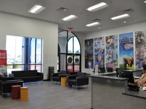 Modern waiting area with black sofas, colorful stools, large windows, and vibrant industrial-themed wall art.