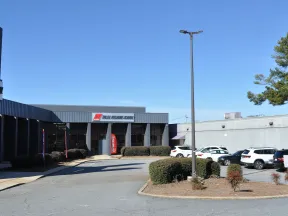 Exterior view of Tulsa Welding School building with parked cars under a clear blue sky.