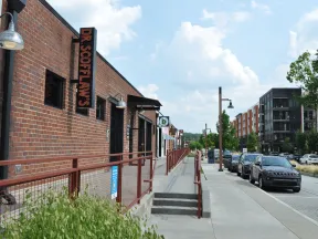 Urban street scene with brick buildings, parked cars, and a sign for Dr. Softlan's on a sunny day.