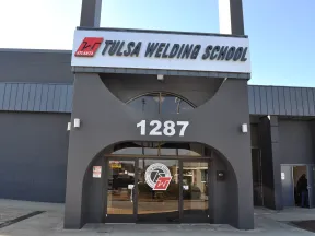 Front entrance of Tulsa Welding School with address 1287 and school logo on glass doors under clear sky.