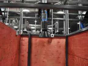 Industrial workspace with red wooden walls and overhead ventilation and duct system in a factory setting.