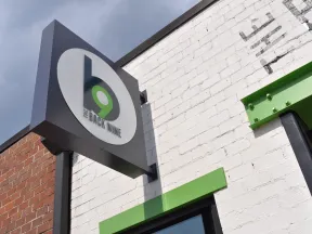 Exterior sign of The Back Nine bar with green and black logo on white and brick wall background.