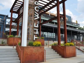 Rustic modern industrial building entrance with large steel beams and yellow flowers on sunny day