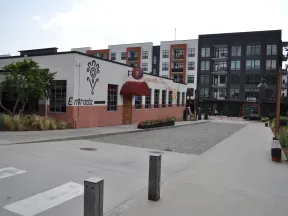 Exterior view of a restaurant with Entrada sign and nearby modern apartment buildings under clear sky