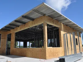 Commercial building under construction with plywood walls steel framing and metal roofing on a sunny day