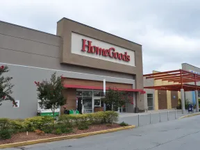 Exterior view of a HomeGoods store with clear signage and landscaped entrance under a cloudy sky.