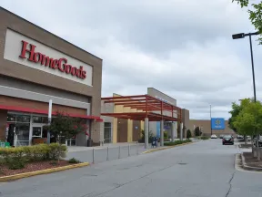 Exterior view of HomeGoods store next to Walmart in a shopping plaza under a cloudy sky.