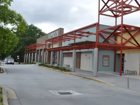 Exterior view of a Joann fabric and craft store with red metal awnings and a tree-lined parking area.