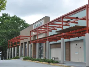 Exterior view of a Joann fabric and craft store with red metal framework and surrounding greenery