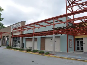 Exterior view of a shopping center with Jo-Ann fabric store and covered walkway with red metal framework.