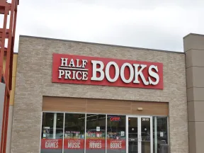Exterior of Half Price Books store with signage advertising cash for games, music, movies, and books.