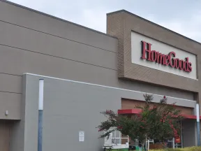 Exterior view of HomeGoods store with large red sign and landscaping including flowering trees.