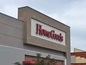 Exterior view of a HomeGoods store sign on a brick and beige building under a cloudy sky.