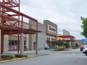 Shopping center exterior with HomeGoods and Walmart stores under a cloudy sky with parked cars.