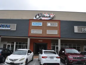 Front view of a commercial building with parked cars and signs for Kumon, Elite Golf, OB/GYN, and dental offices.