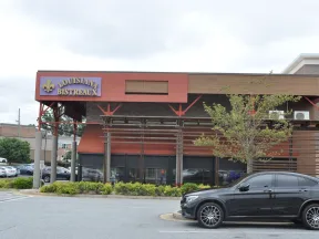 Louisiana Bistreaux restaurant exterior with a parked black car and surrounding greenery in a shopping area.