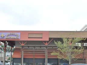 Louisiana Bistreaux restaurant exterior with sign, orange awnings, wooden pergola, and a tree in front.