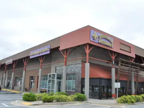 Corner view of a shopping plaza with Louisiana Bistreaux restaurant and various stores under a cloudy sky.