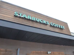 Exterior view of a Starbucks Coffee shop with wooden paneling and green signage on a clear day