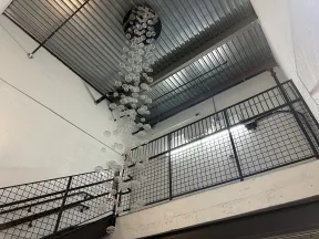 Modern indoor stairwell with metal railings and hanging glass bubble chandelier under industrial ceiling.