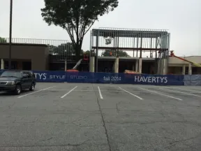 Construction site with Havertys Style Studio banner and a partially built steel structure behind a parking lot.