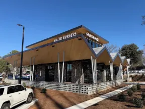 Modern restaurant building with unique angled roof and signage for Killer Burgers and Grindhouse on sunny day.