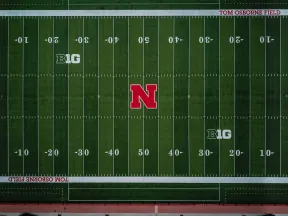 Aerial view of Nebraska Huskers football field with green turf, red logo, and Big Ten Conference markings.