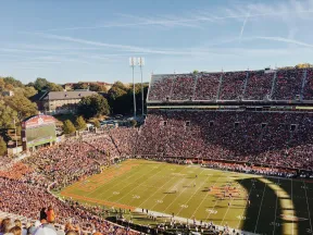 Aerial view of a crowded football stadium during a game with fans filling the stands under a clear sky.